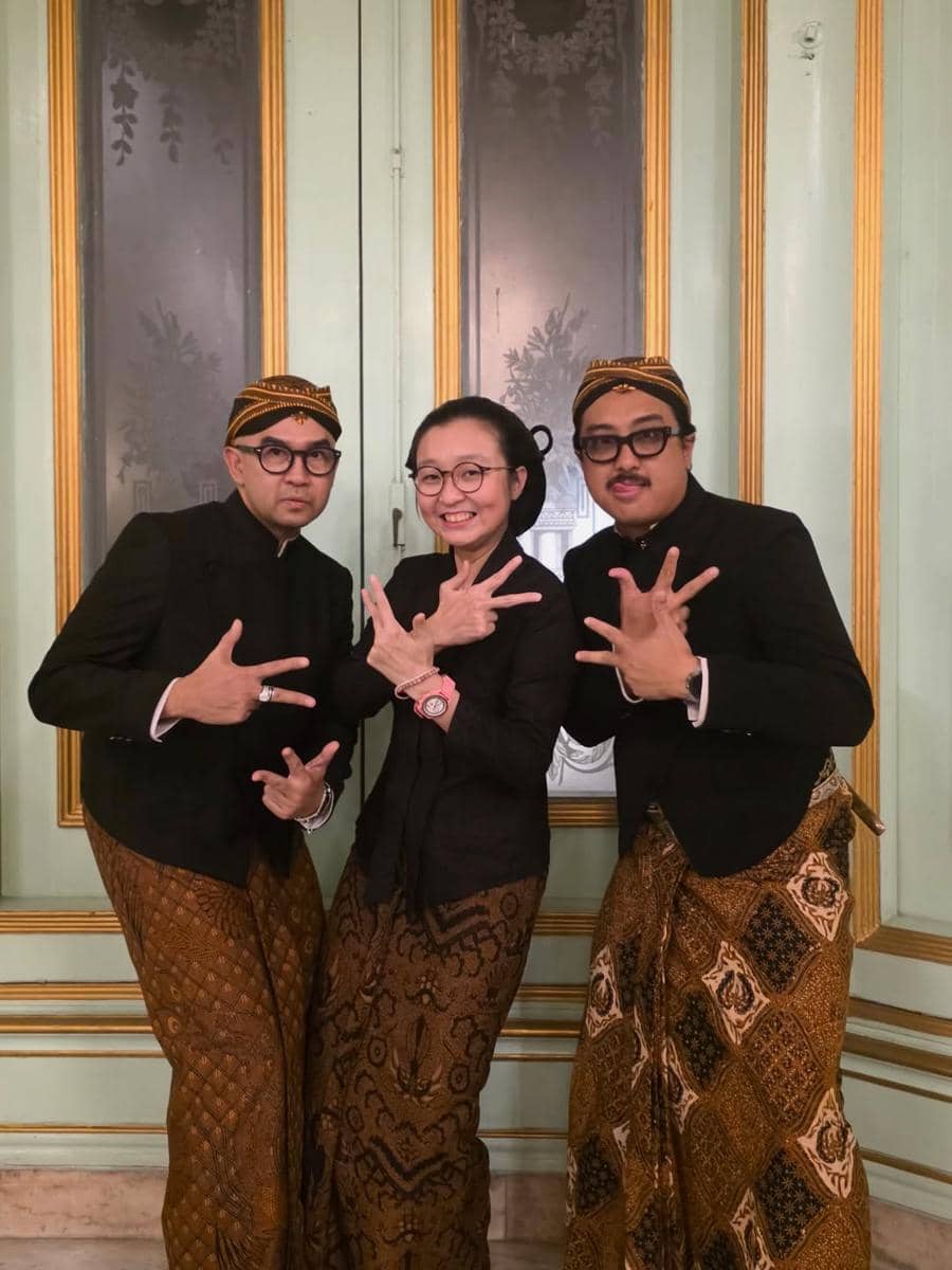 Tiga orang mengenakan busana adat Jawa lengkap dengan blangkon dan jarik berpose bersama di acara Kirab Pusaka Dalem Malam 1 Suro di Mangkunegaran.