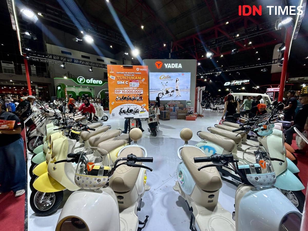 Deretan skuter listrik Yadea dipamerkan di stan pameran PRJ 2026 dengan pengunjung yang melihat dan mencoba kendaraan listrik tersebut.