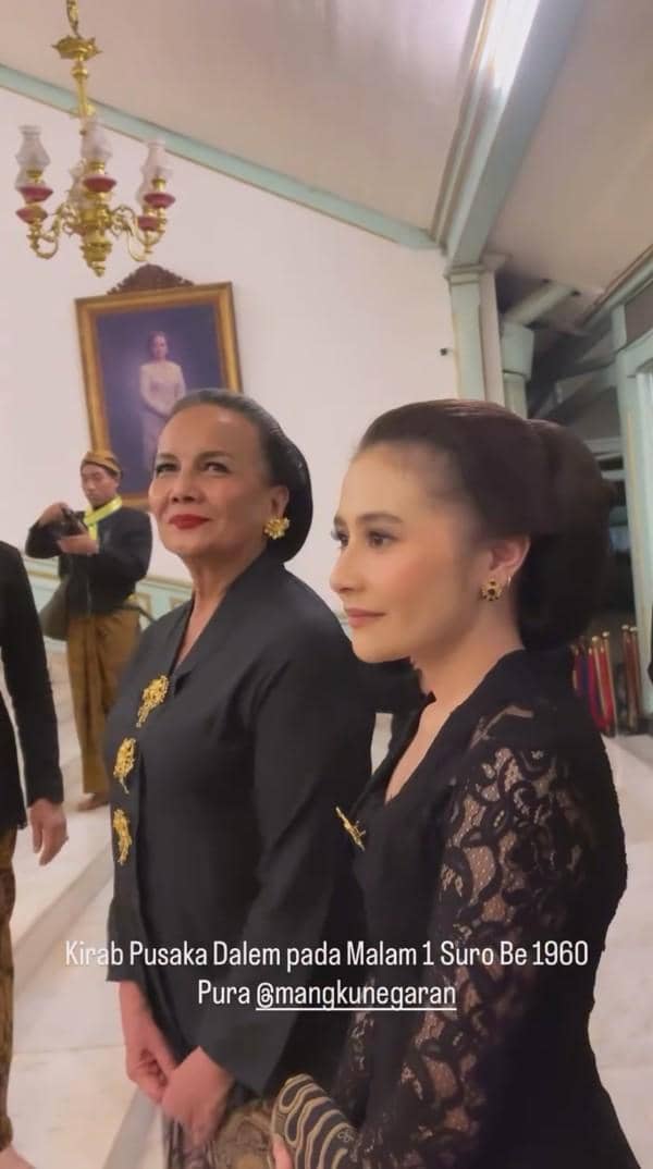 Dua perempuan mengenakan kebaya hitam dengan sanggul tradisional menghadiri Kirab Pusaka Dalem Malam 1 Suro di Pura Mangkunegaran.