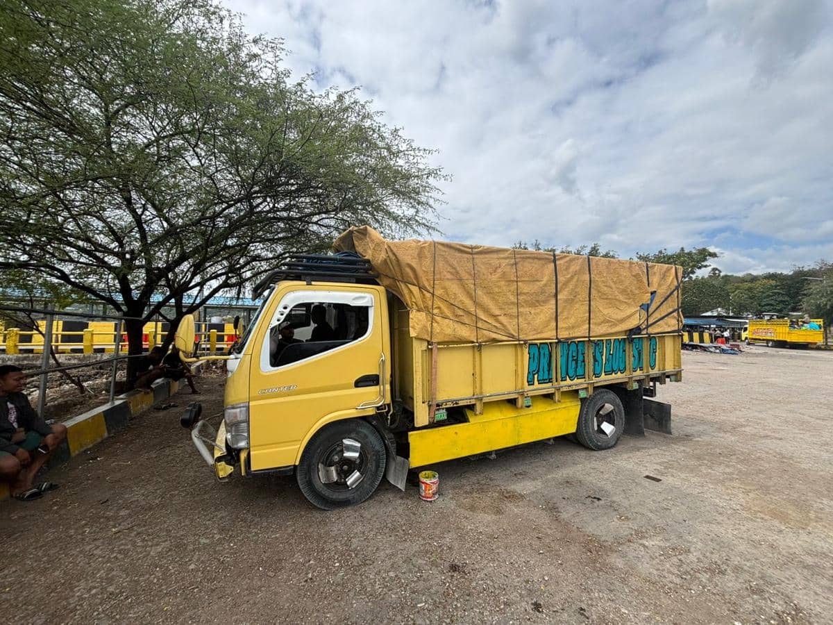 Truk kuning bermuatan tertutup terpal cokelat parkir di area pelabuhan Kupang, diduga terkait penyelundupan minyak tanah.
