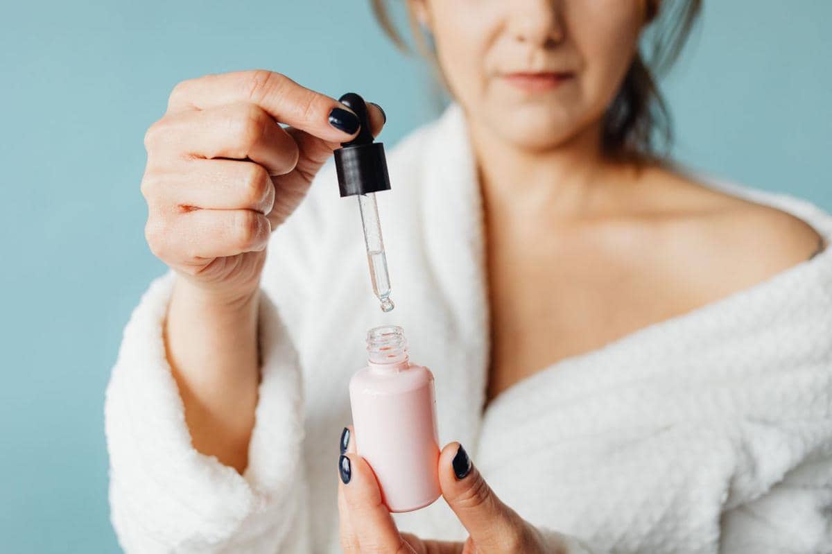 ilustrasi seorang wanita dewasa yang mengoleskan serum dengan pipet