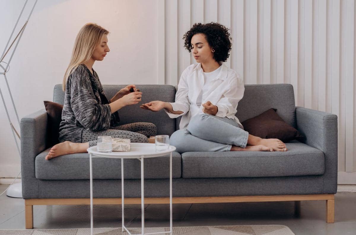 ilustrasi dua wanita duduk di sofa sambil mempraktikkan aromaterapi