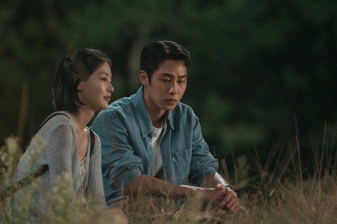 Dua karakter duduk berdampingan di rerumputan pada malam hari dalam adegan drama Korea Doctor on the Edge.