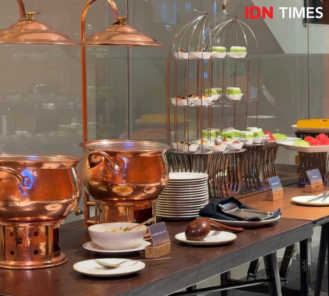 Meja buffet di Wolon All Day Dining, Lobby Elais by ARTOTEL Medan, dengan panci tembaga, piring saji, dan aneka hidangan penutup.