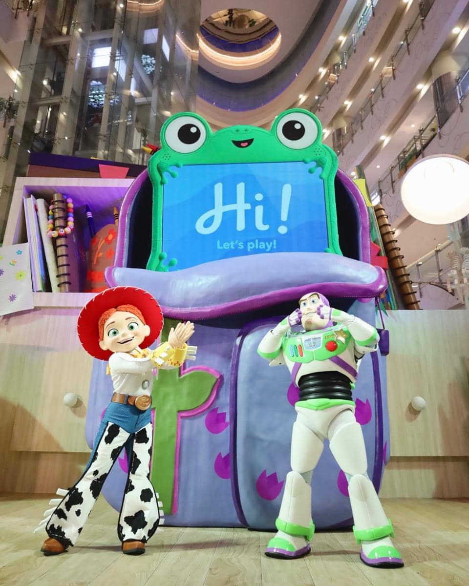 Dua karakter Toy Story berdiri di depan instalasi bertema mainan warna-warni di Central Park Mall Jakarta dengan latar gedung bertingkat.