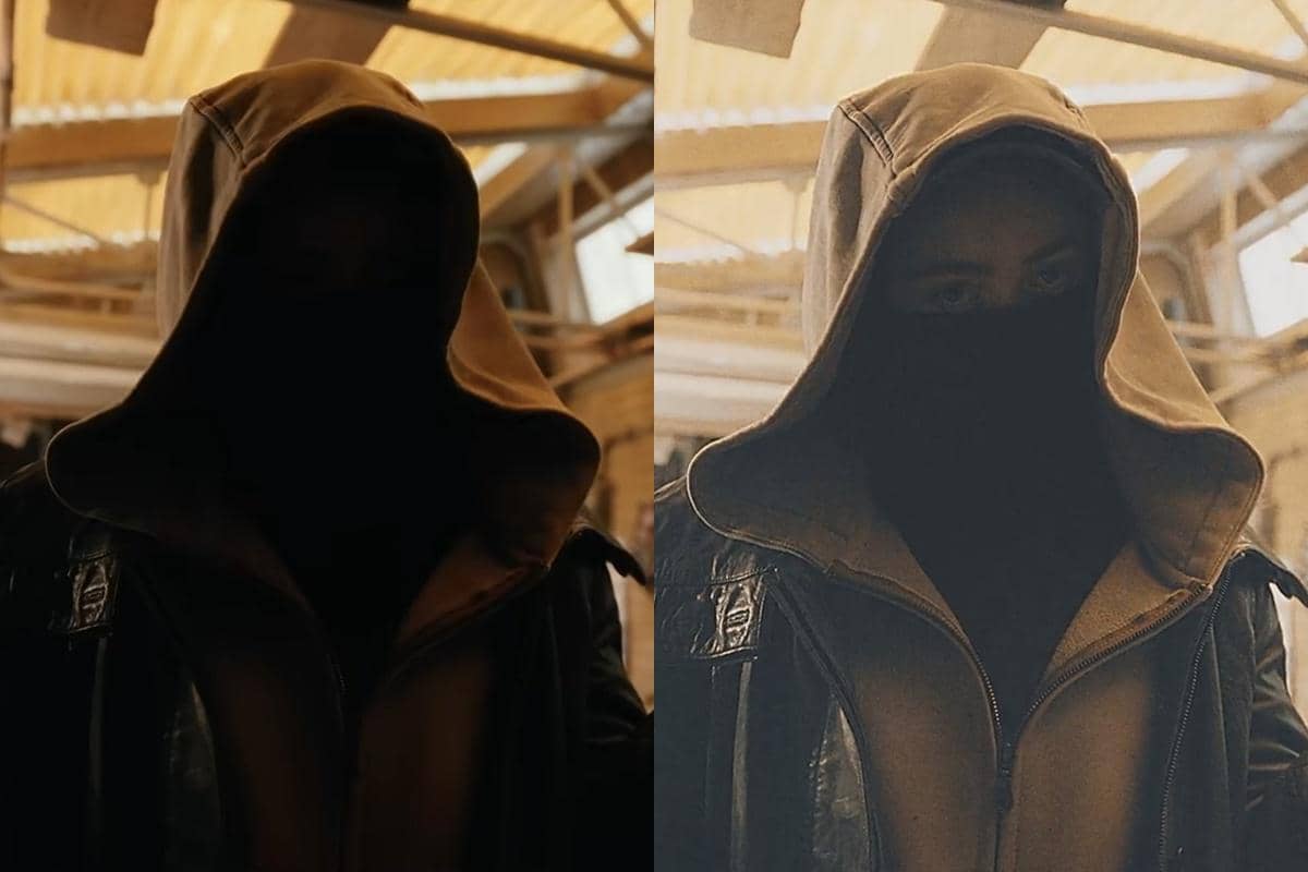 Sosok berkerudung dengan jaket kulit dan masker hitam berdiri di dalam bangunan dengan pencahayaan hangat dari atap kaca.