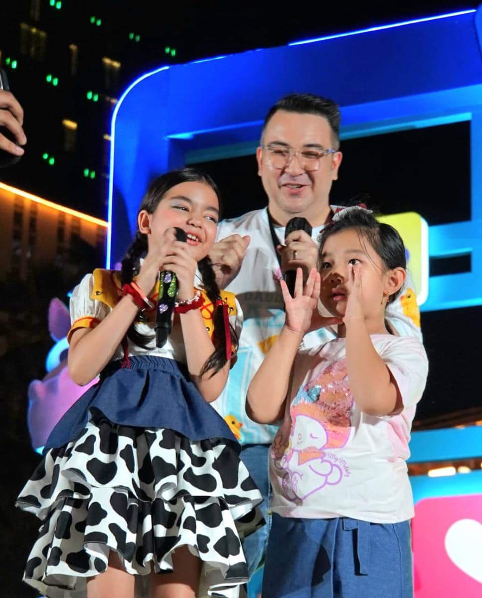 Dua anak bernyanyi dengan gembira di atas panggung bersama seorang pria saat acara instalasi Toy Story 5 di Central Park Mall Jakarta.