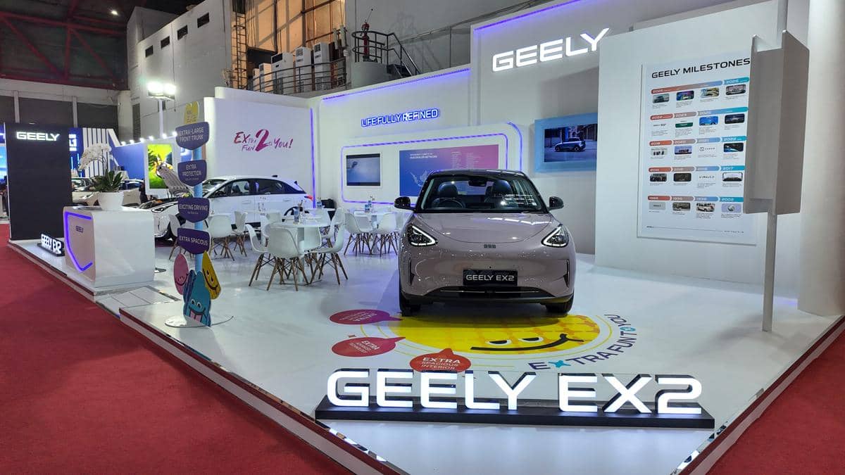 Mobil listrik Geely EX2 dipamerkan di booth Geely dengan desain modern dan pencahayaan ungu di sebuah pameran otomotif.