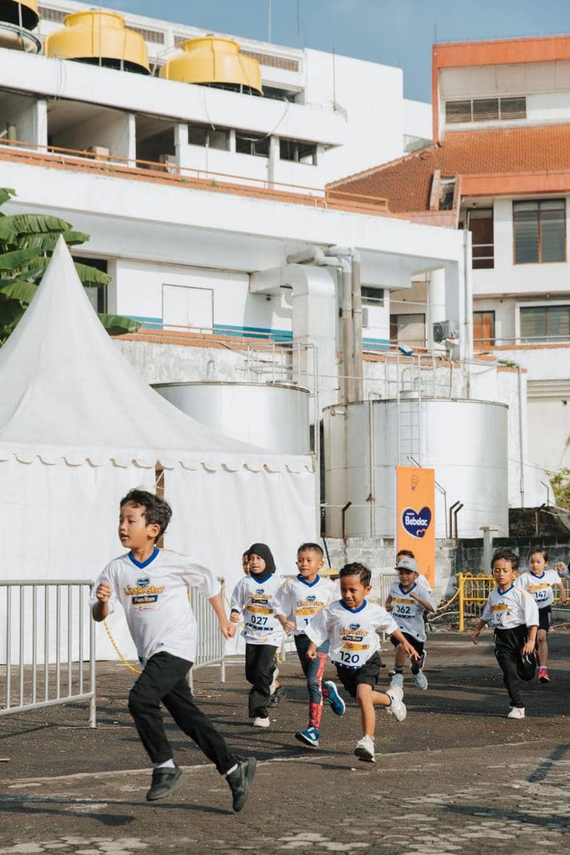 Anak-anak berlari dengan semangat mengenakan kaus bertuliskan Little Star Fun Run 2026 di area luar ruangan Surabaya.