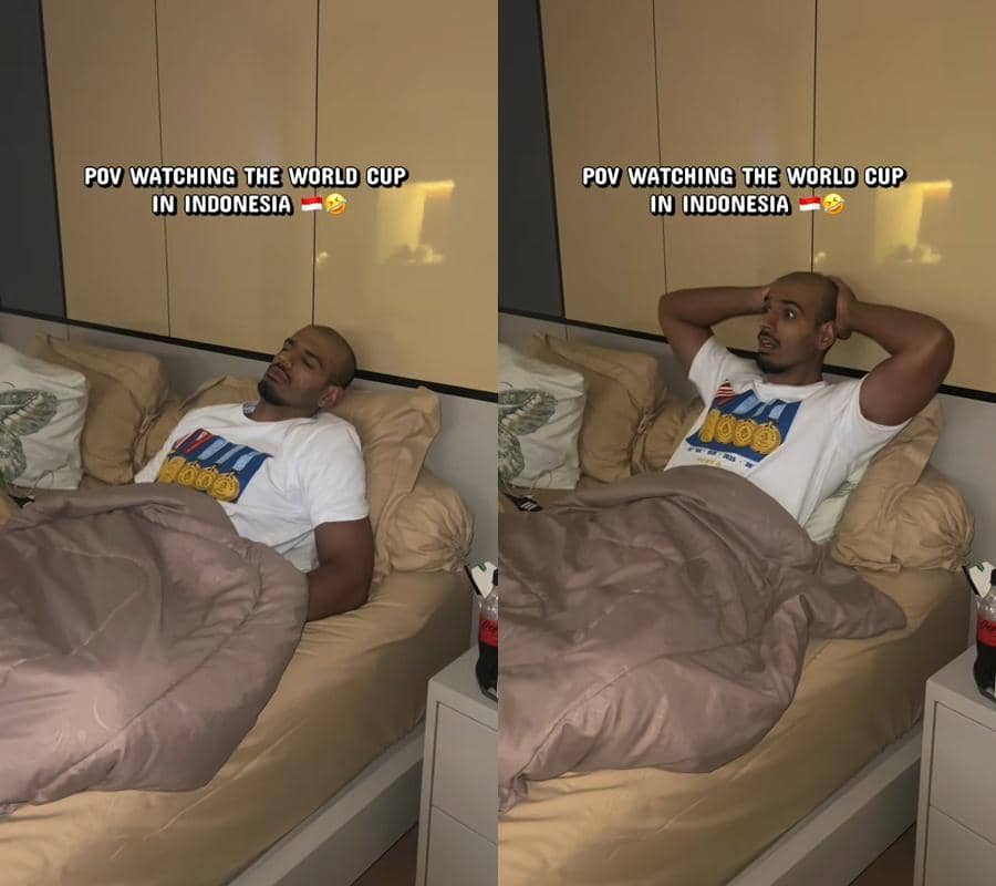 Seorang pria berbaring di tempat tidur dengan ekspresi lelah dan terkejut saat menonton Piala Dunia di malam hari di Indonesia.