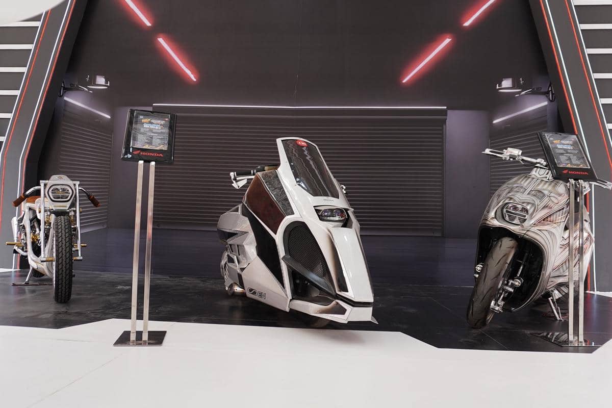 Tiga motor konsep futuristik dengan desain unik dipamerkan di area bertema modern dengan pencahayaan merah dan hitam.