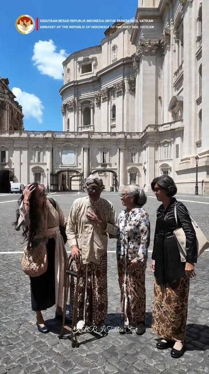 Butet Kertaredjasa mengenakan busana tradisional Jawa berbincang di halaman luar bangunan megah di Vatikan dengan suasana cerah.
