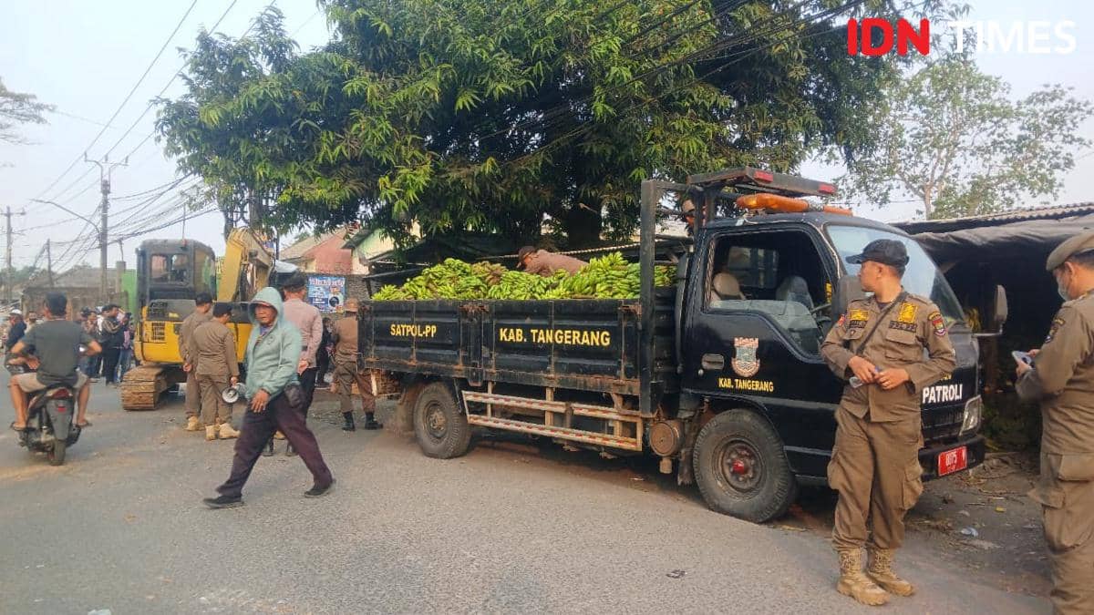 Petugas Satpol PP Kabupaten Tangerang menertibkan pedagang di lahan bekas TPPS dengan truk patroli dan alat berat di lokasi.