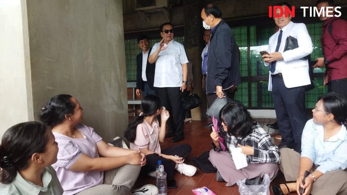 Beberapa petinggi kampus berbincang dengan sekelompok mahasiswa yang duduk di lantai area kampus Universitas HKBP Nommensen.