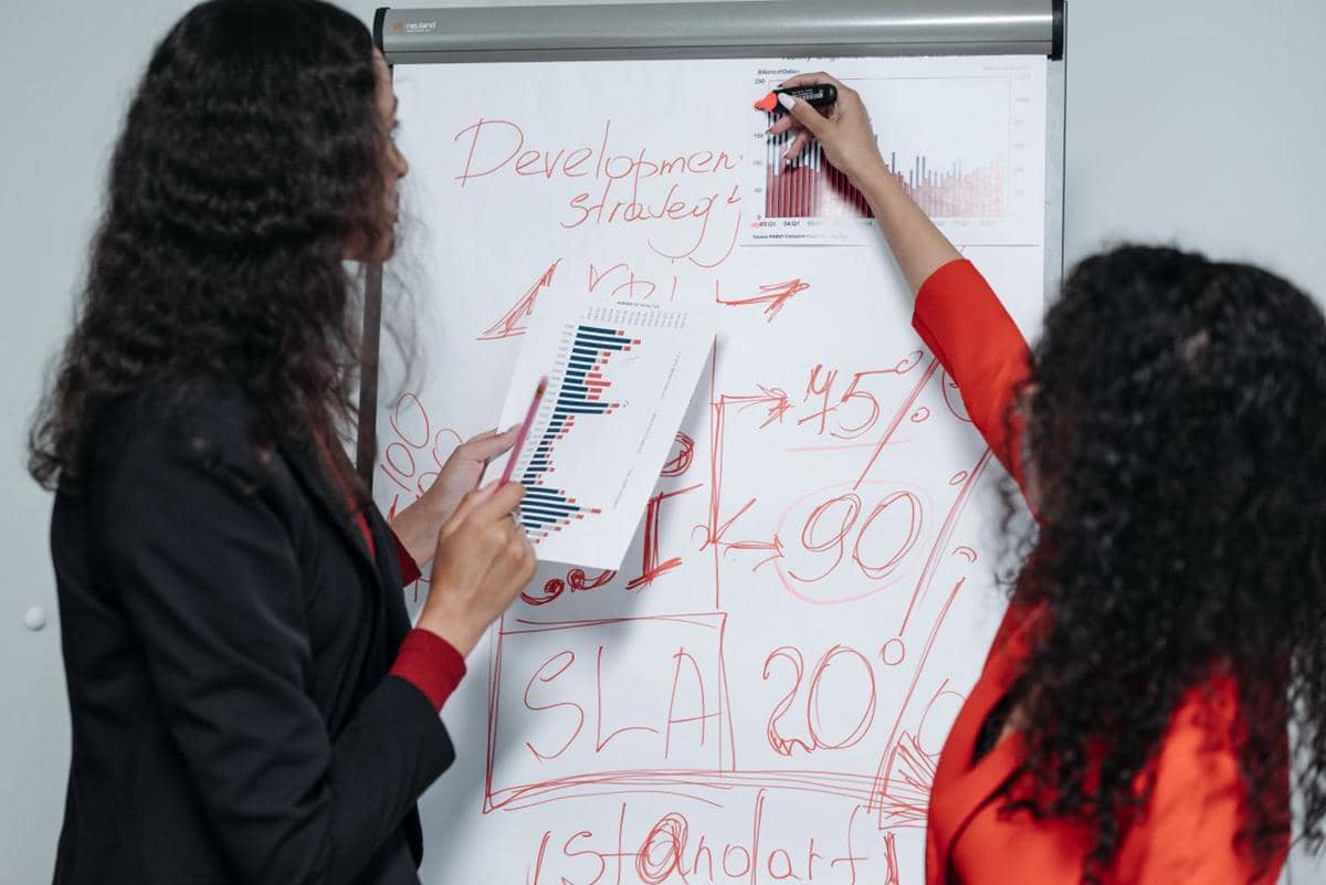 ilustrasi dua wanita profesional berdiskusi dan menyusun strategi pengembangan bisnis
