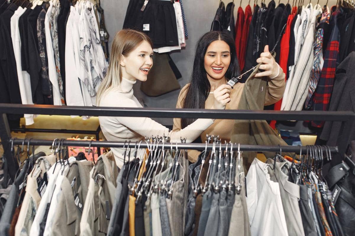 ilustrasi dua wanita dengan gembira berbelanja pakaian di butik trendi