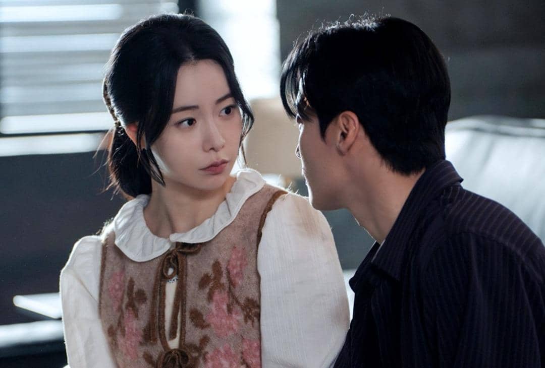 Dua karakter dalam drama Korea My Royal Nemesis saling menatap dengan ekspresi serius di dalam ruangan bercahaya lembut.