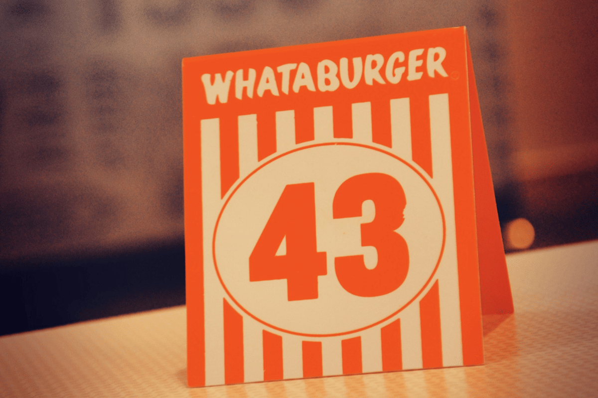 Nomor meja oranye putih dengan tulisan Whataburger dan angka 43 di atas meja restoran cepat saji.