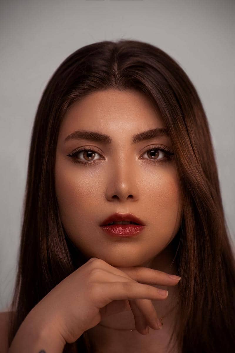 Wajah seorang wanita dengan riasan make up shimmer dan highlight yang memberikan efek glow alami pada kulitnya.