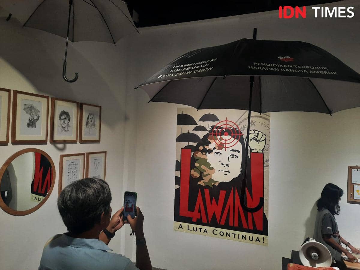 Pengunjung memotret instalasi seni bertema perlawanan dengan poster bergambar wajah dan tulisan 'Lawan' di ARTJOG 2026.
