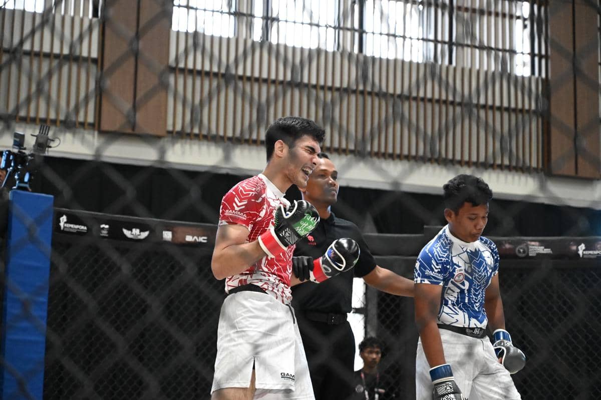 Petarung MMA mengenakan seragam merah merayakan kemenangan di dalam arena setelah pertandingan Kejurnas MMA 2026 di Bogor.