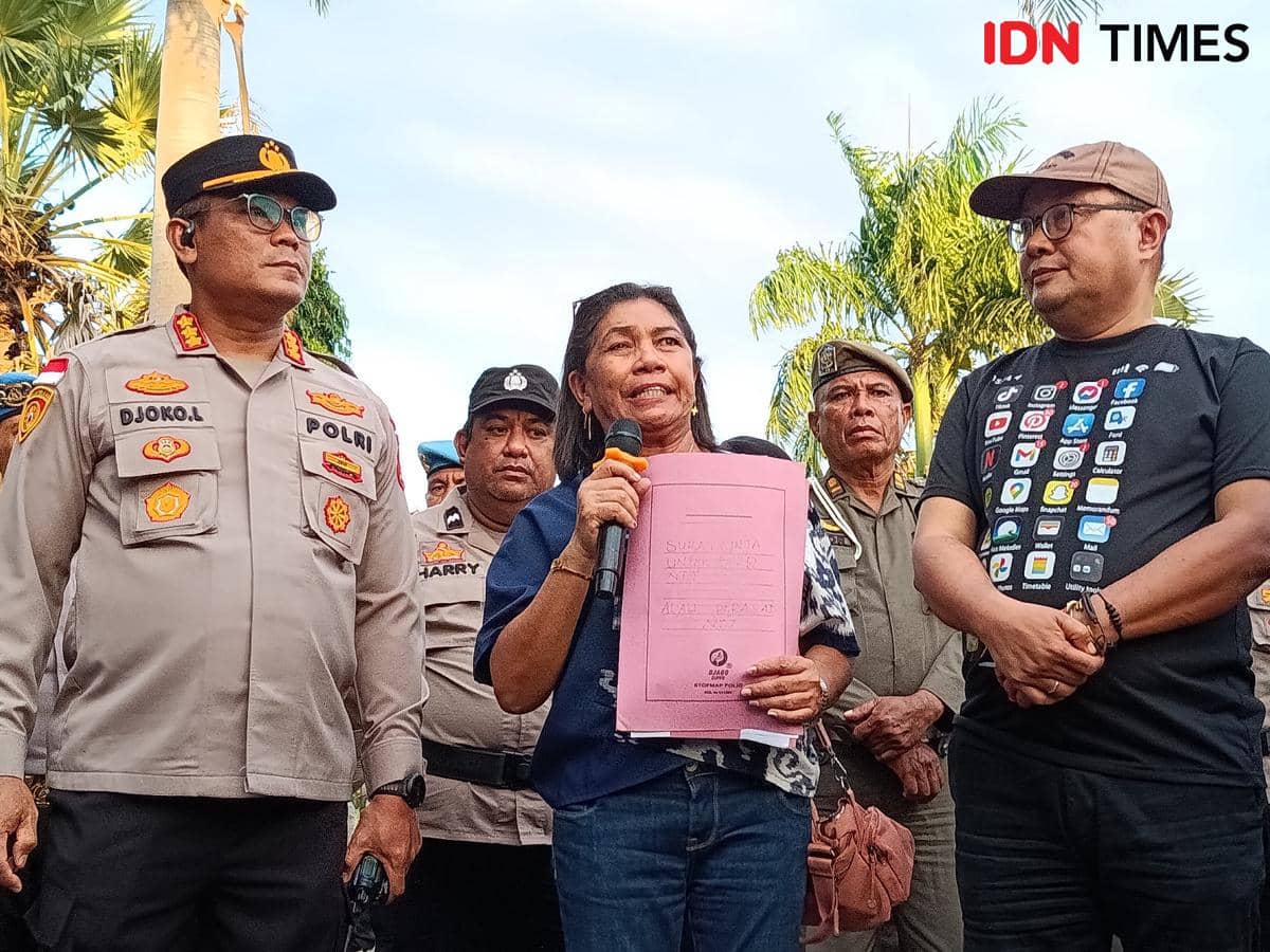 Perwakilan anggota DPRD NTT memegang surat berwarna merah muda dari demonstran Aliansi Mahasiswa Perisai Kota Kupang, didampingi aparat kepolisian.