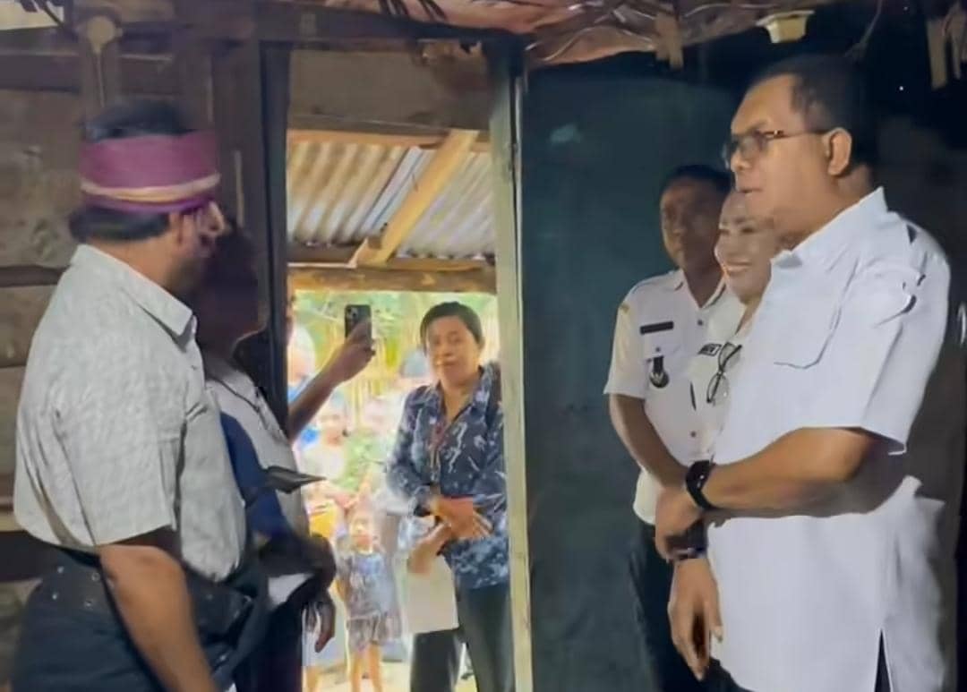 Seorang pejabat daerah bersama rombongan meninjau kondisi rumah warga kurang mampu di sebuah perkampungan sederhana.