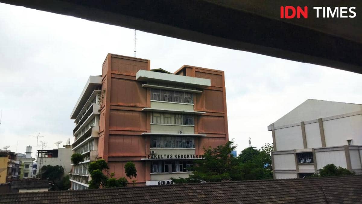 Gedung Fakultas Kedokteran Universitas HKBP Nommensen berwarna oranye dengan beberapa jendela besar di tengah area kampus.