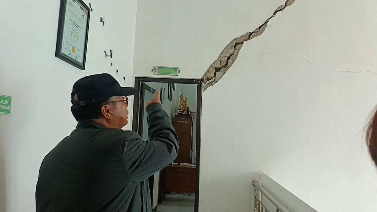 Seorang pejabat menunjuk retakan besar di dinding gedung Rumah Sakit Umum Daerah Waikabubak saat melakukan peninjauan kerusakan.