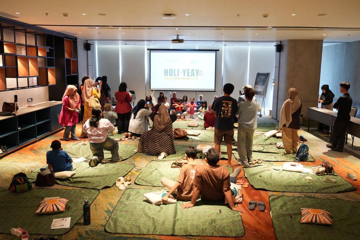 Suasana kegiatan staycation keluarga di sebuah ruangan hotel di Tangerang dengan peserta duduk di atas tikar menghadap layar proyektor.