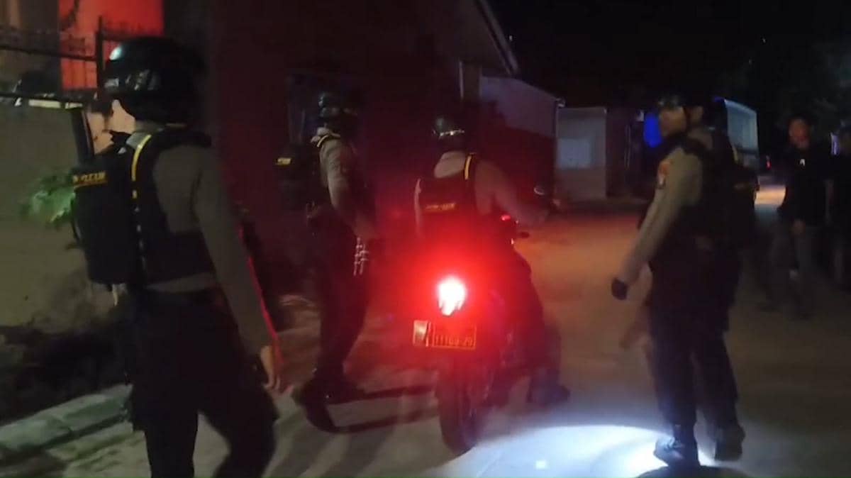 Beberapa polisi berseragam lengkap melakukan penggerebekan di sebuah rumah pada malam hari di Kecamatan Tamalanrea, Makassar.