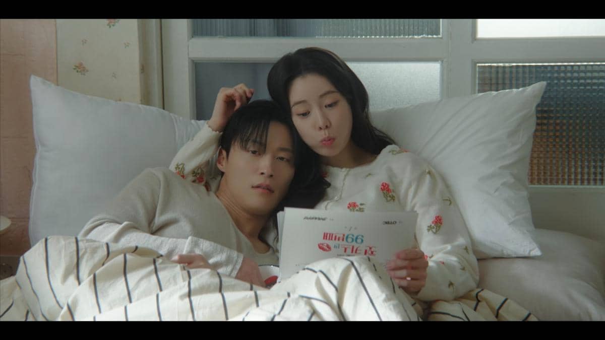 Dua karakter dalam drama My Royal Nemesis berbaring di tempat tidur sambil membaca naskah bersama dengan suasana hangat dan intim.