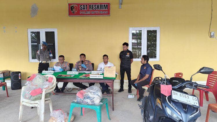 Petugas Polres Rote Ndao duduk di meja dengan barang bukti dan sepeda motor di depan ruang Sat Reskrim saat konferensi pers kasus pembunuhan.