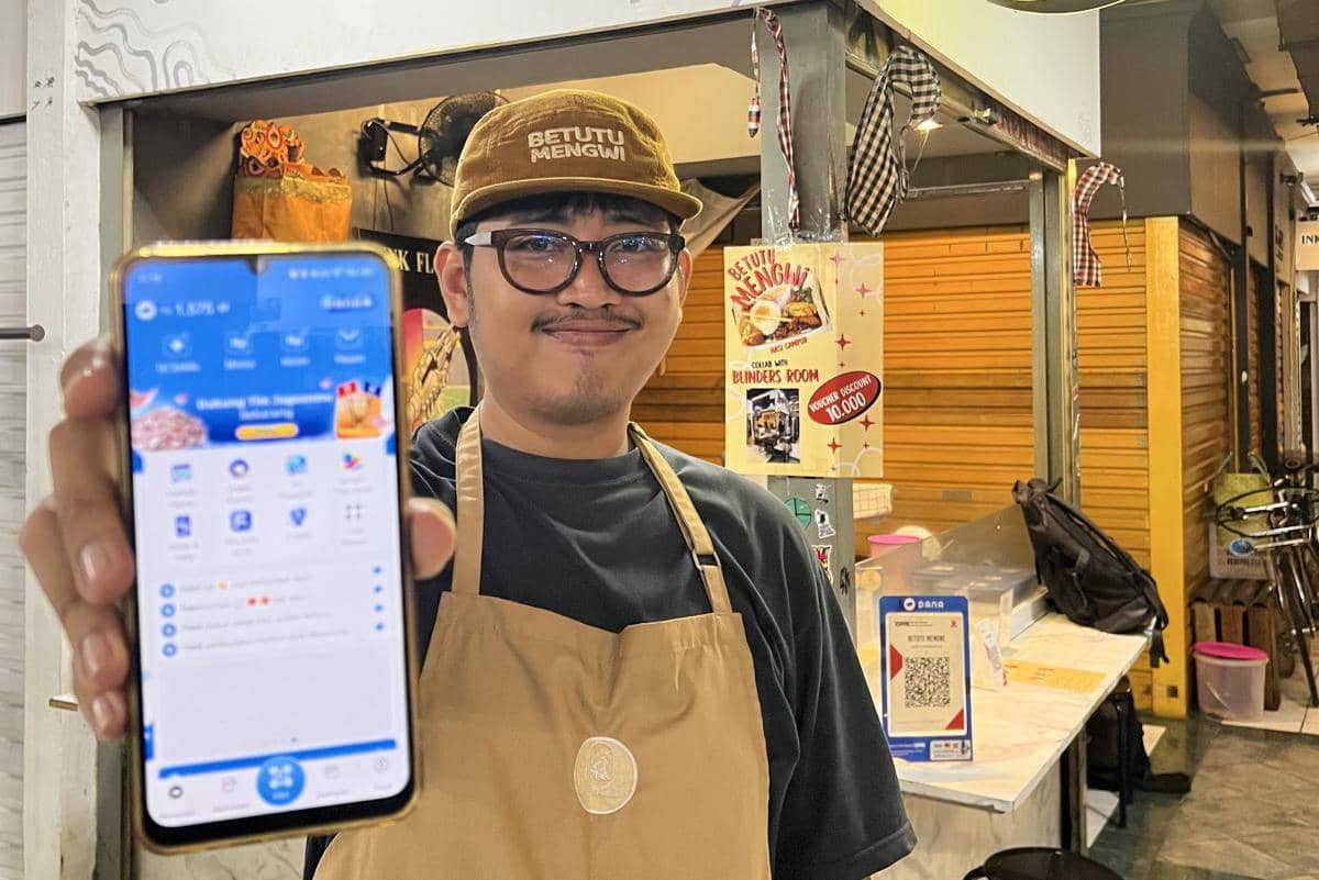 Pemilik kedai Betutu Mengwi, I Nyoman Yoga Gamma, sedang membuka aplikasi DANA.