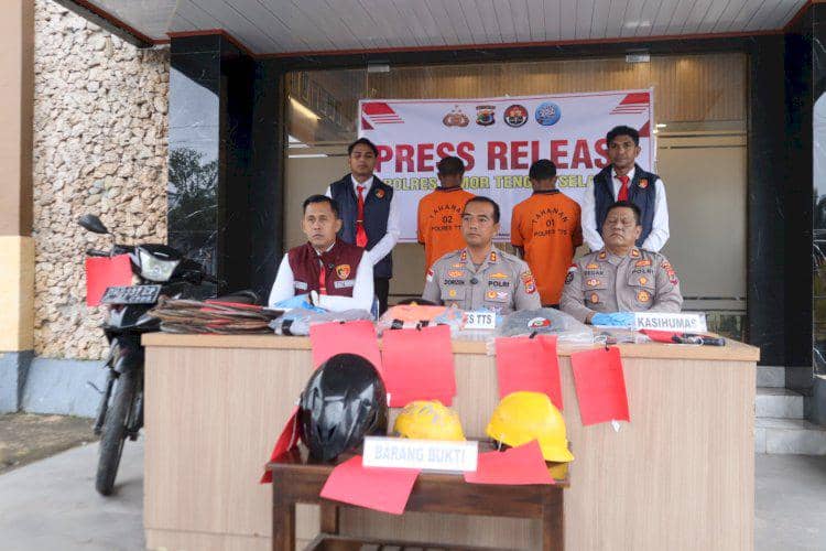 Petugas Polres TTS merilis pelaku dan barang bukti kasus pencurian kabel penangkal petir, termasuk helm dan sepeda motor di meja konferensi pers.