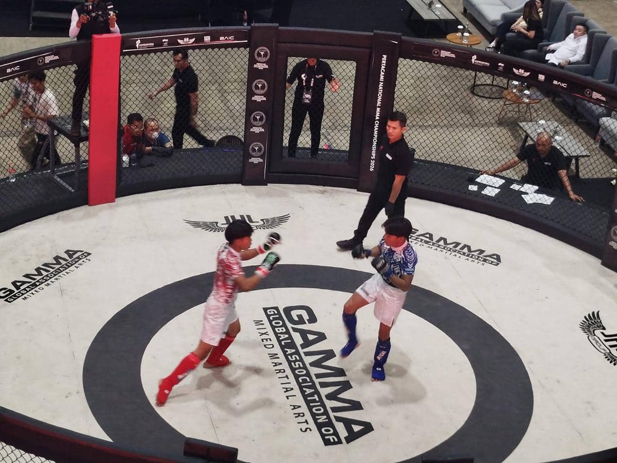Dua atlet MMA bertanding di dalam arena oktagon pada Kejurnas MMA 2026 di Bogor dengan wasit mengawasi jalannya pertandingan.
