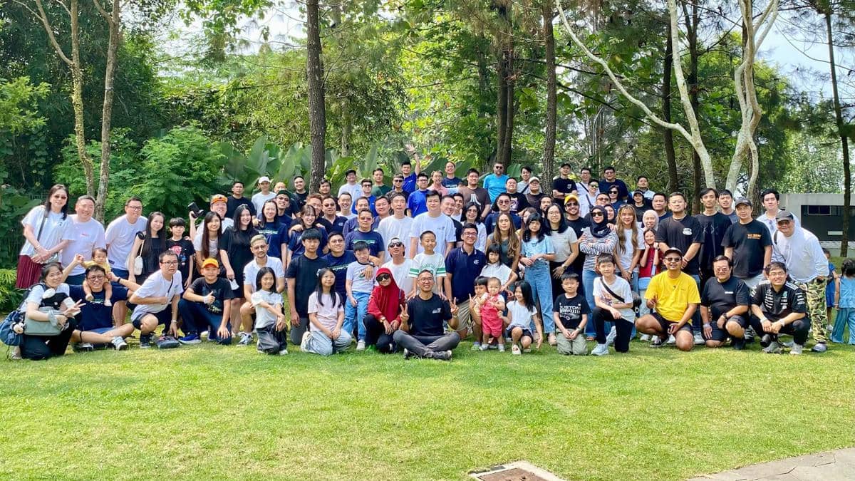 Ratusan peserta berfoto bersama di area taman hijau dalam acara bertema JDM Run dengan suasana santai dan penuh kebersamaan.