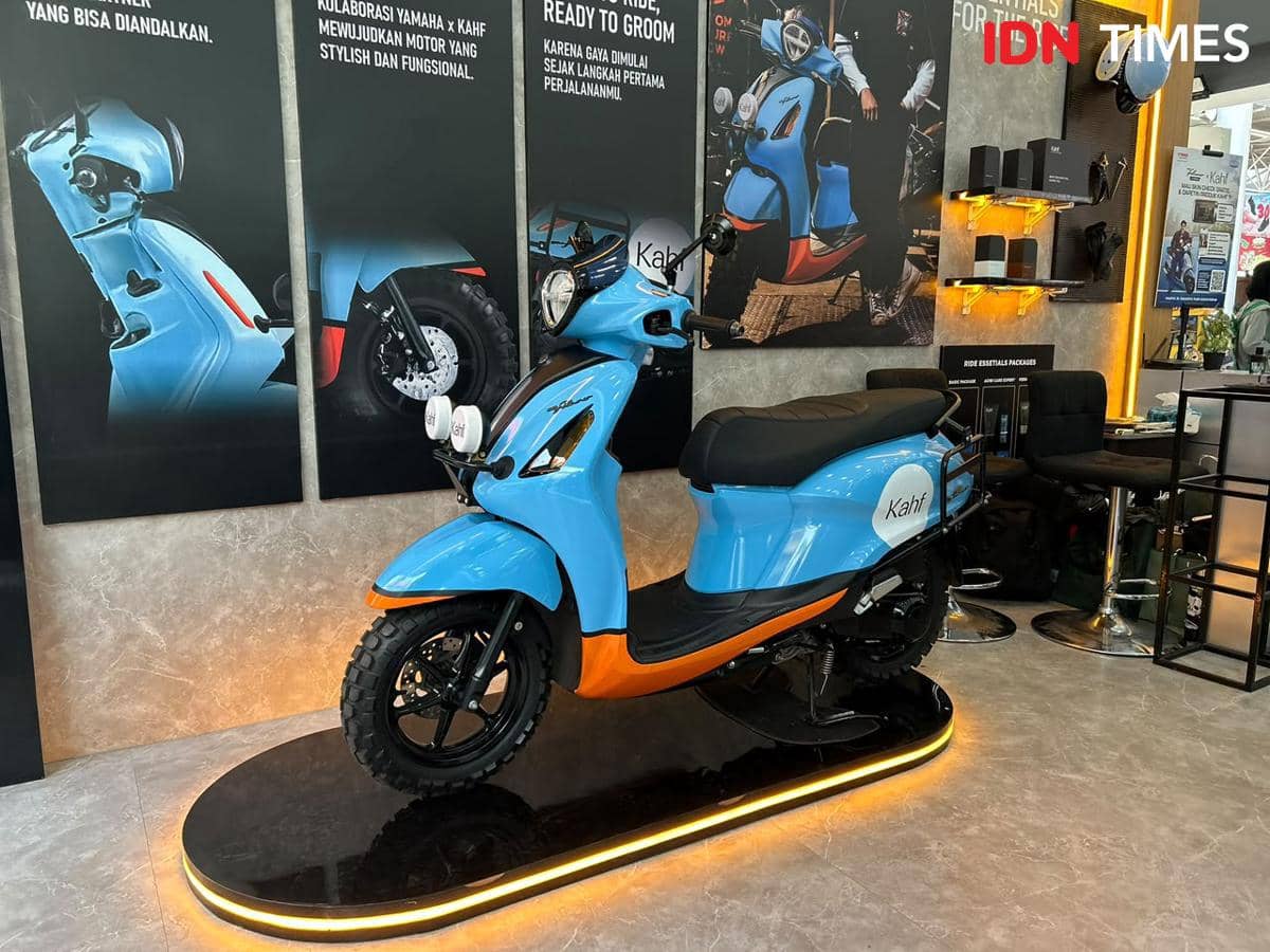 Skuter berwarna biru dan oranye dengan tema Classy Modern Explorer dipamerkan di sebuah booth dengan pencahayaan hangat dan dekorasi modern.