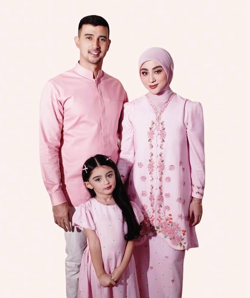 Sebuah keluarga terdiri dari pria, wanita berhijab, dan anak perempuan kecil mengenakan busana serasi berwarna merah muda.