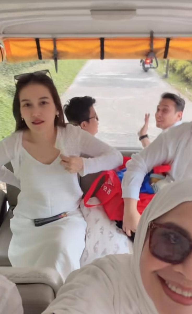 Sejumlah orang mengenakan pakaian putih sedang duduk di kendaraan terbuka saat berwisata di area hijau Cisarua.