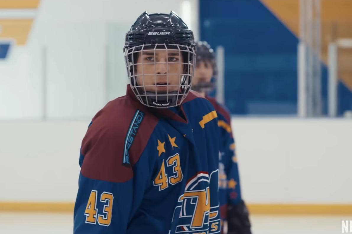 Pemain hoki es mengenakan seragam biru dan helm pelindung sedang berada di arena es dalam cuplikan serial Zero Chill.
