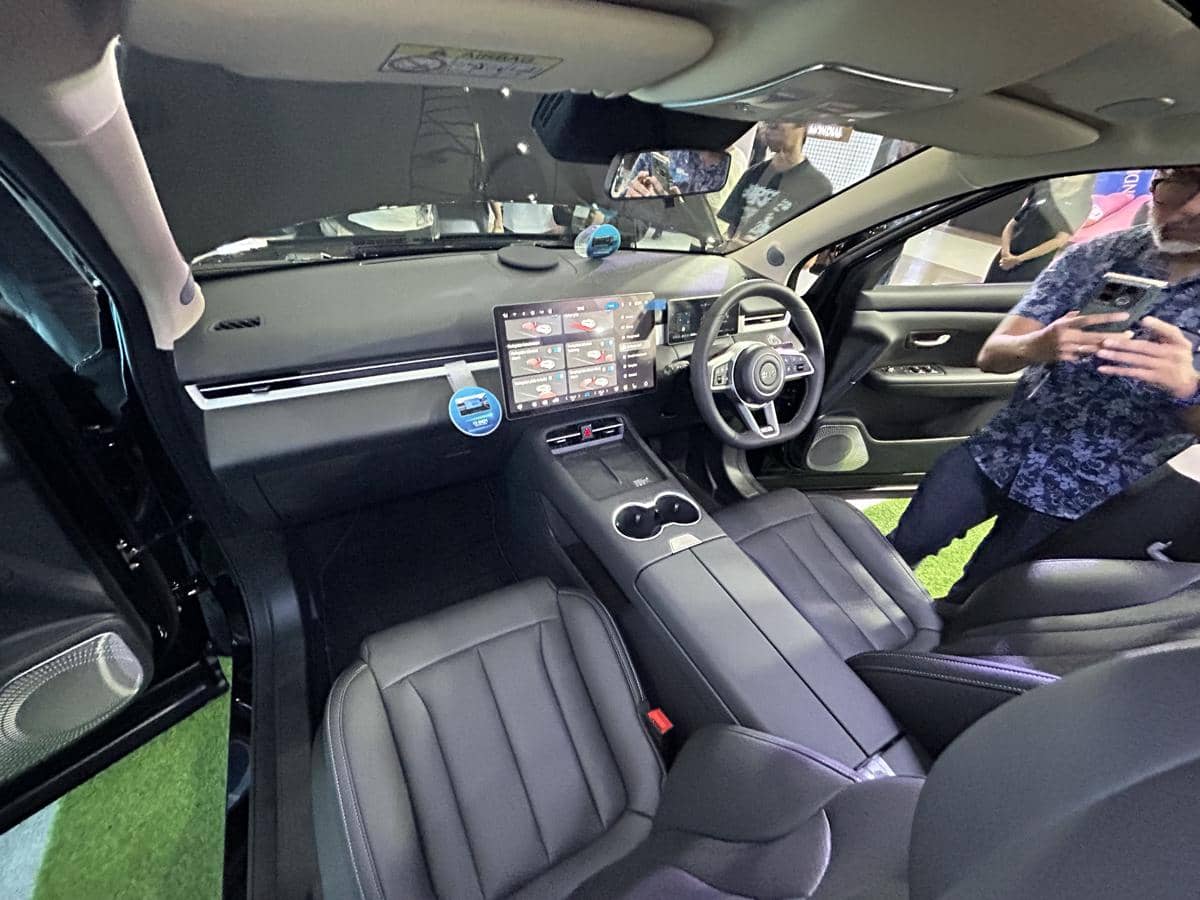 Interior mobil DFSK E5 Plus dengan desain modern, layar sentuh besar di tengah dasbor, dan jok kulit hitam elegan.