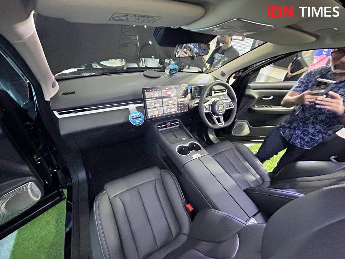 Interior mobil DFSK E5 Plus dengan desain modern, layar sentuh besar di tengah dasbor, dan jok kulit hitam elegan.