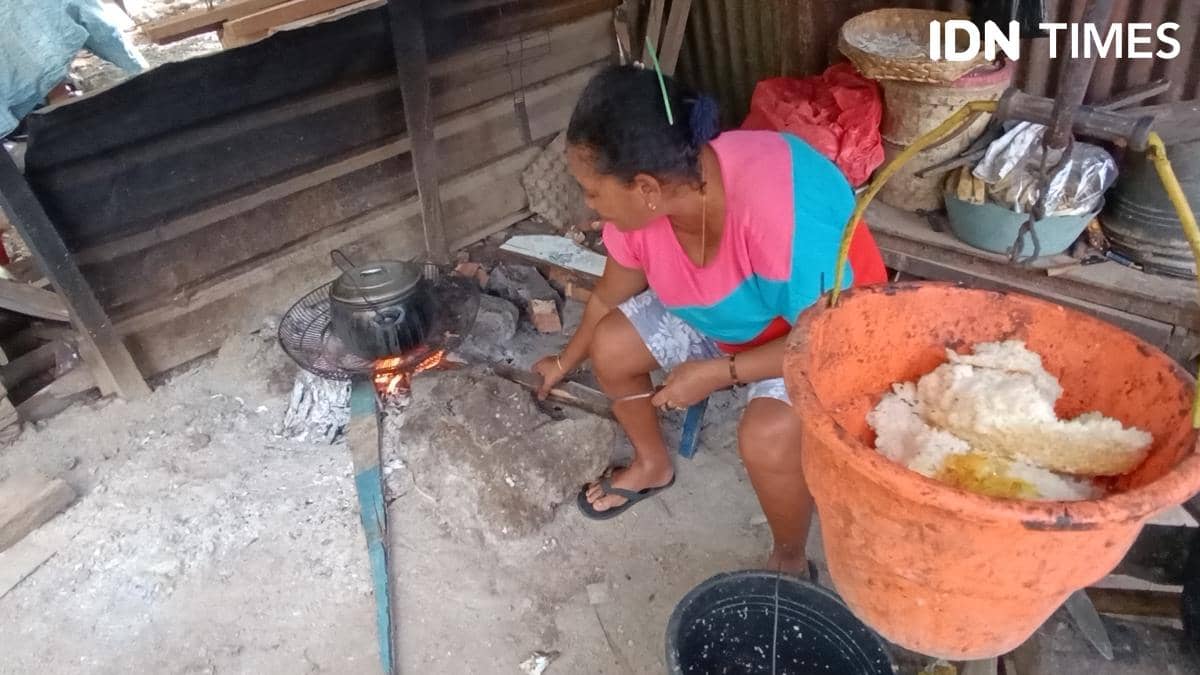 Seorang warga Kampung Nelayan di Kelurahan Oesapa, Kota Kupang, sedang memasak di tungku api menggunakan kayu sisa bangkai kapal.