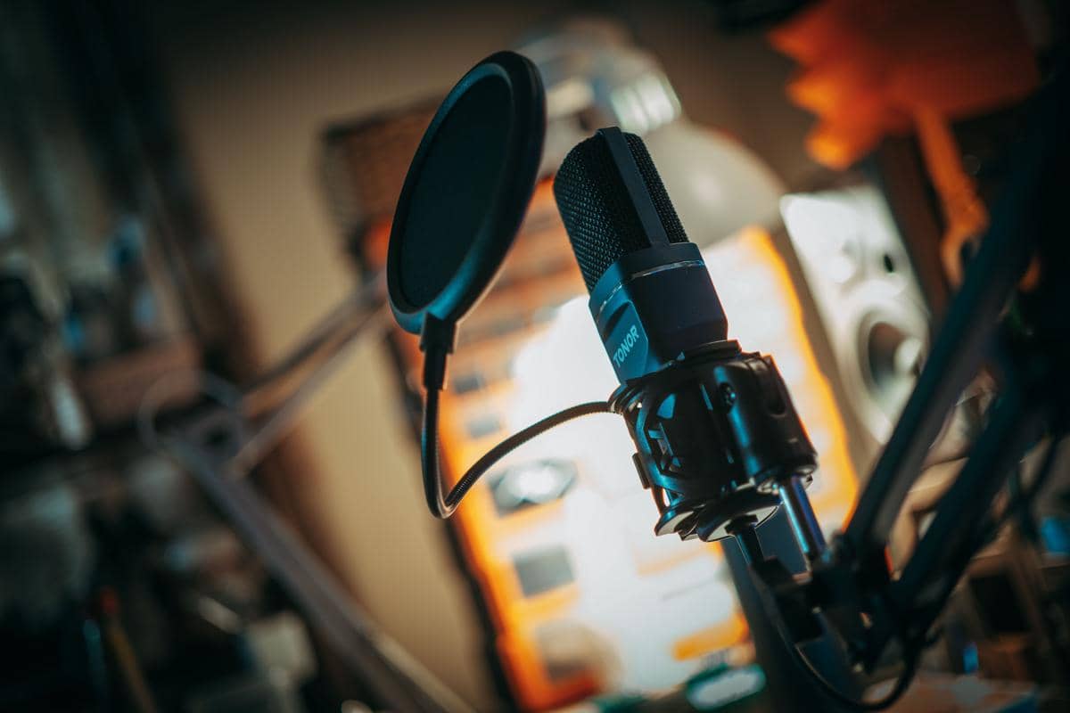 Mikrofon studio dengan pop filter di depan, digunakan untuk proses perekaman suara, voice over, atau dubbing profesional.