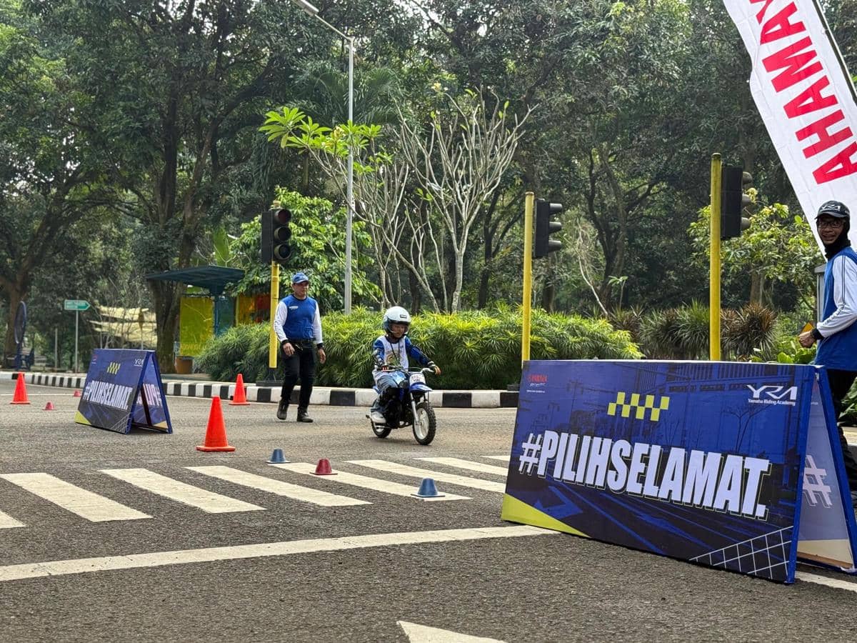 Seorang anak mengendarai motor kecil di area latihan keselamatan berkendara di Taman Lalu Lintas Buperta Cibubur bersama instruktur.