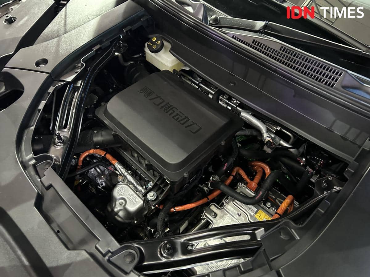 Komponen mesin mobil listrik DFSK E5 Plus dengan kabel oranye dan sistem pendingin terlihat di ruang mesin kendaraan.