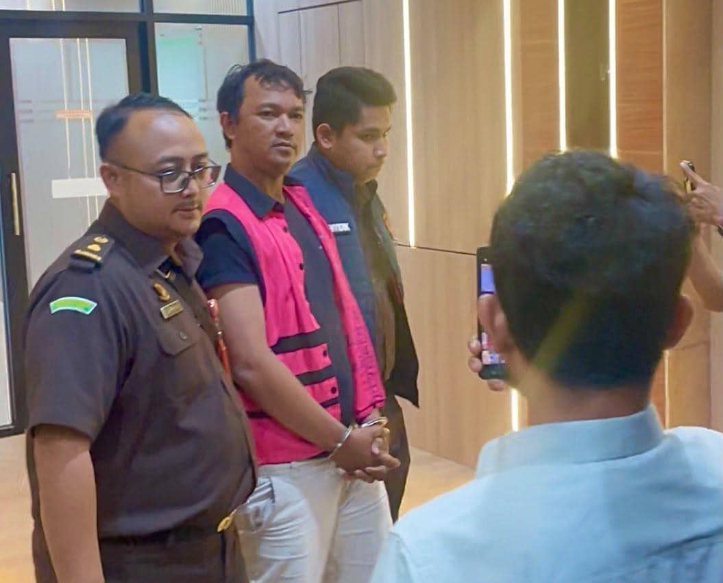 Petugas Kejaksaan Negeri Tangerang Selatan menggiring seorang pria berompi merah muda yang diduga terlibat kasus korupsi gadai syariah di Pegadaian.