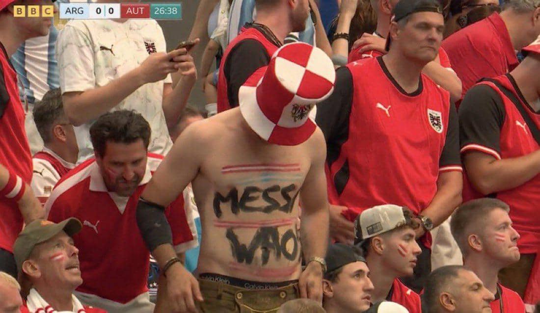 Seorang suporter Austria bertelanjang dada dengan tulisan di tubuhnya di antara penonton pertandingan Argentina vs Austria di stadion.