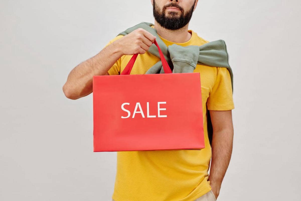ilustrasi seseorang berbaju kuning memegang tas belanja merah